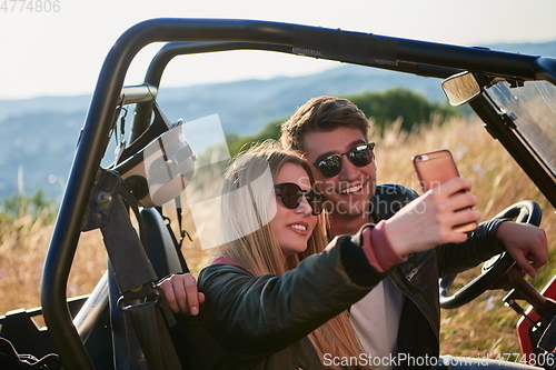 Image of couple enjoying beautiful sunny day taking selfie picture while driving a off road buggy