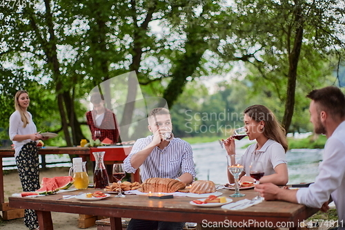 Image of friends having picnic french dinner party outdoor during summer holiday