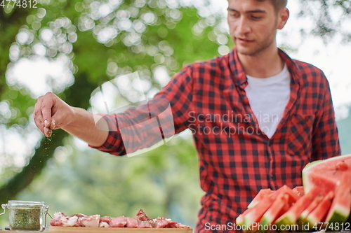 Image of man putting spices on raw meat for barbecue