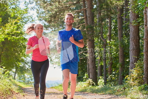 Image of couple enjoying in a healthy lifestyle while jogging on a country road