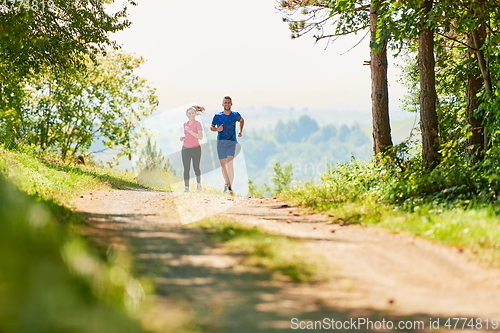 Image of couple enjoying in a healthy lifestyle while jogging on a country road