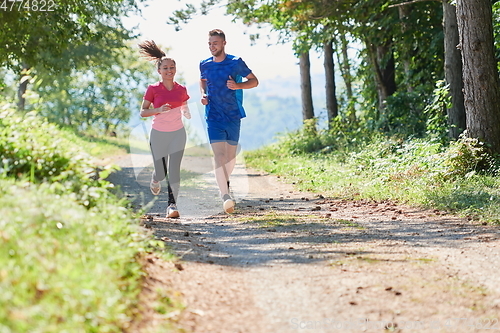 Image of couple enjoying in a healthy lifestyle while jogging on a country road