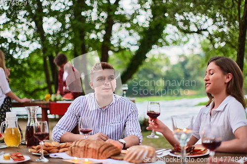 Image of friends having picnic french dinner party outdoor during summer holiday