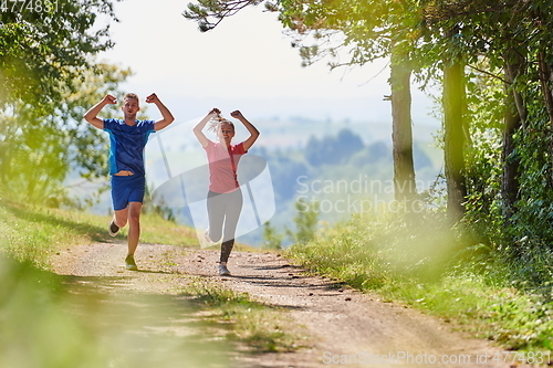 Image of couple enjoying in a healthy lifestyle while jogging on a country road