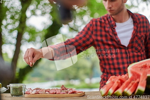 Image of man putting spices on raw meat for barbecue