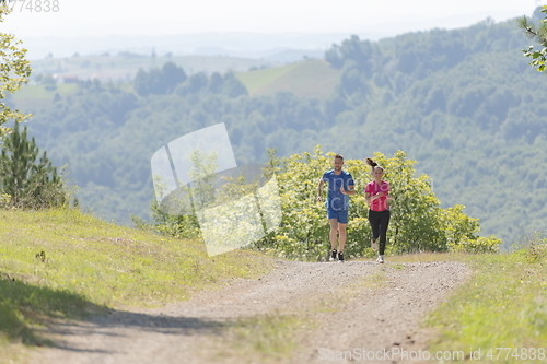 Image of couple enjoying in a healthy lifestyle while jogging on a country road