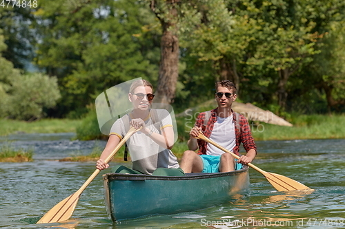 Image of friends are canoeing in a wild river