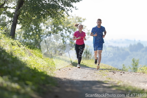 Image of couple enjoying in a healthy lifestyle while jogging on a country road