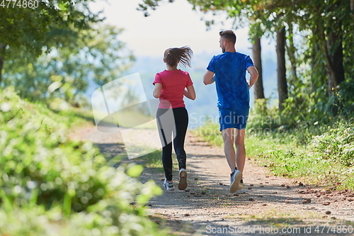 Image of couple enjoying in a healthy lifestyle while jogging on a country road