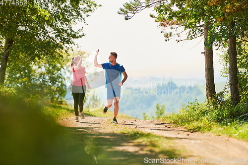 Image of couple enjoying in a healthy lifestyle while jogging on a country road