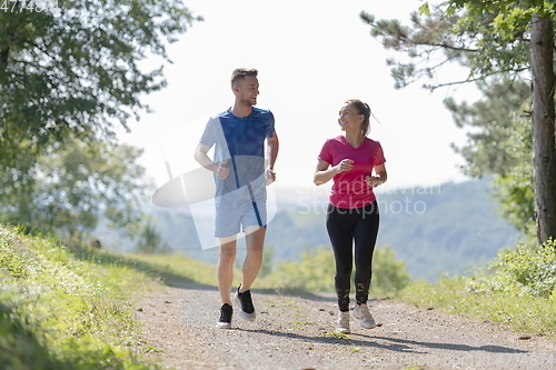 Image of couple enjoying in a healthy lifestyle while jogging on a country road