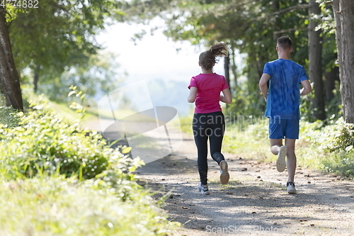 Image of couple enjoying in a healthy lifestyle while jogging on a country road