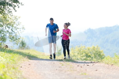 Image of couple enjoying in a healthy lifestyle while jogging on a country road