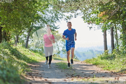 Image of couple enjoying in a healthy lifestyle while jogging on a country road