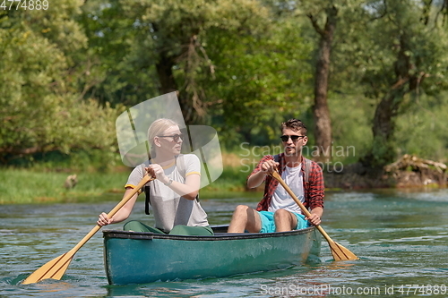 Image of friends are canoeing in a wild river