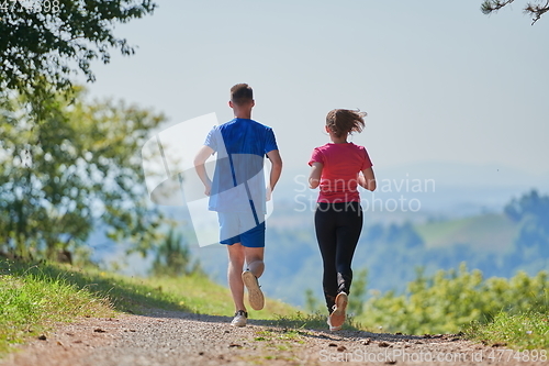Image of couple enjoying in a healthy lifestyle while jogging on a country road