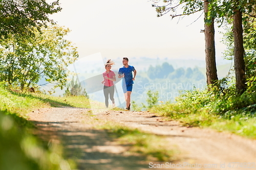 Image of couple enjoying in a healthy lifestyle while jogging on a country road