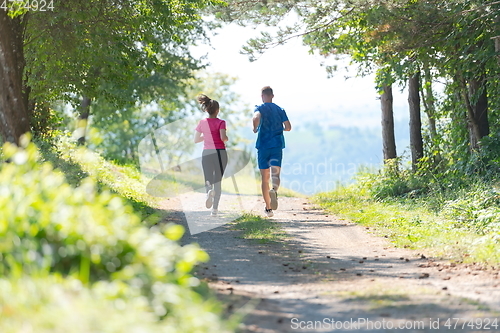 Image of couple enjoying in a healthy lifestyle while jogging on a country road