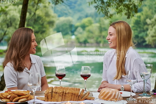 Image of girlfriends having picnic french dinner party outdoor