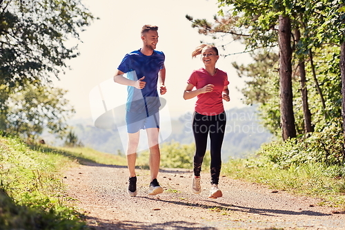 Image of couple enjoying in a healthy lifestyle while jogging on a country road