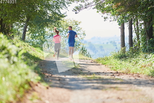 Image of couple enjoying in a healthy lifestyle while jogging on a country road