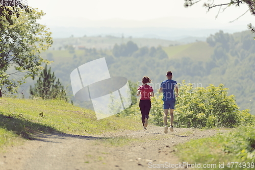 Image of couple enjoying in a healthy lifestyle while jogging on a country road