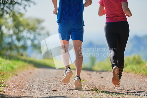 Image of couple enjoying in a healthy lifestyle while jogging on a country road