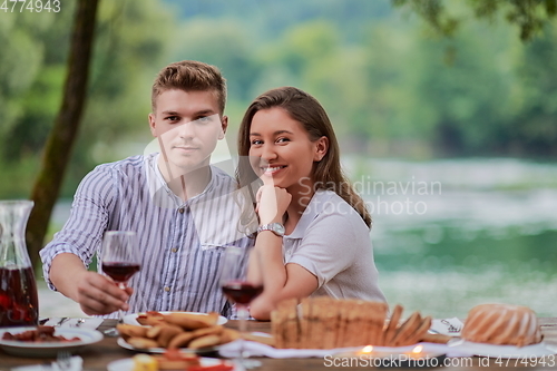 Image of couple toasting red wine glass while having picnic french dinner party outdoor
