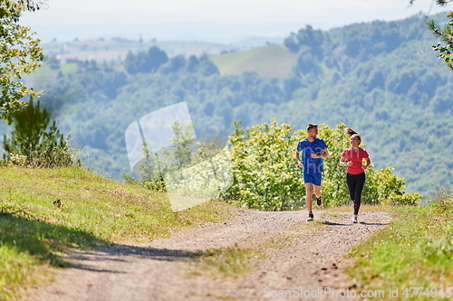 Image of couple enjoying in a healthy lifestyle while jogging on a country road