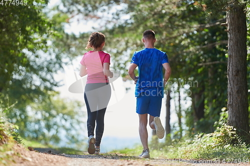 Image of couple enjoying in a healthy lifestyle while jogging on a country road