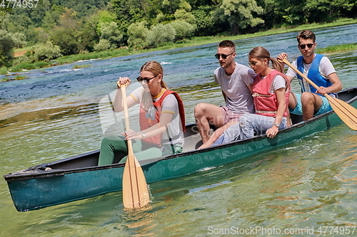 Image of Group adventurous explorer friends are canoeing in a wild river