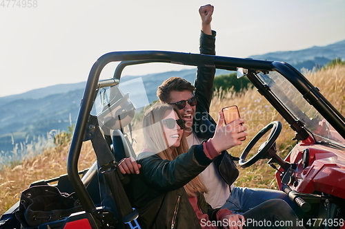 Image of couple enjoying beautiful sunny day taking selfie picture while driving a off road buggy