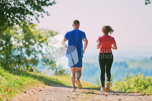 Image of couple enjoying in a healthy lifestyle while jogging on a country road