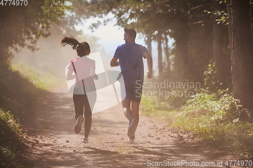 Image of couple enjoying in a healthy lifestyle while jogging on a country road