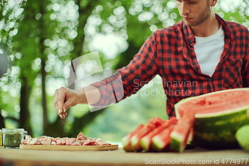 Image of man putting spices on raw meat for barbecue