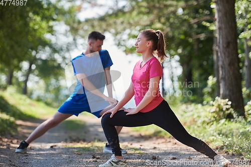 Image of couple enjoying in a healthy lifestyle warming up and stretching before jogging