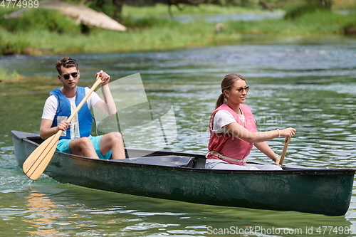 Image of friends are canoeing in a wild river