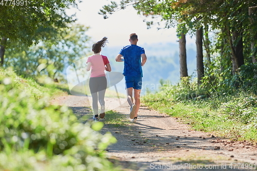 Image of couple enjoying in a healthy lifestyle while jogging on a country road
