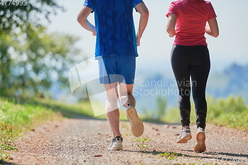 Image of couple enjoying in a healthy lifestyle while jogging on a country road