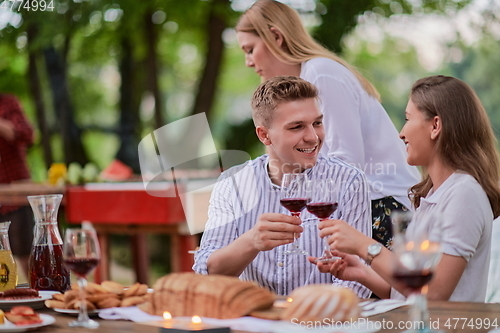 Image of friends having picnic french dinner party outdoor during summer holiday