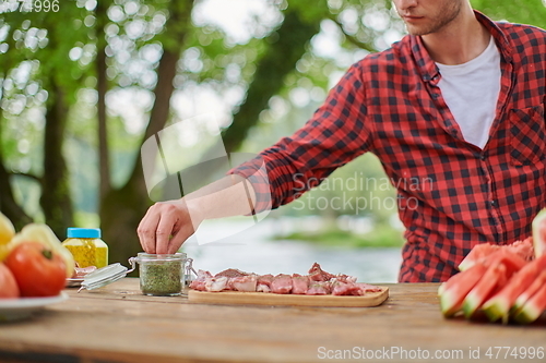Image of man putting spices on raw meat for barbecue