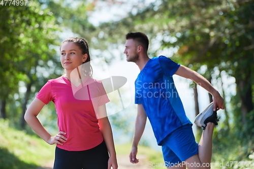 Image of couple enjoying in a healthy lifestyle warming up and stretching before jogging