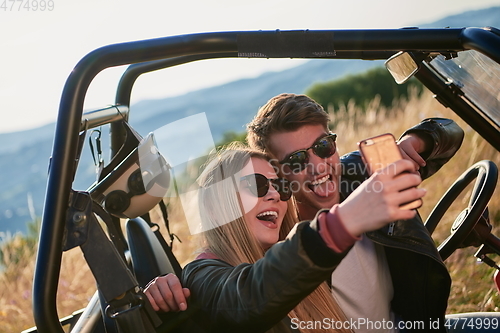 Image of couple enjoying beautiful sunny day taking selfie picture while driving a off road buggy