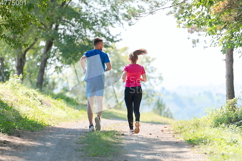 Image of couple enjoying in a healthy lifestyle while jogging on a country road