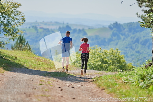 Image of couple enjoying in a healthy lifestyle while jogging on a country road