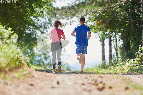 Image of couple enjoying in a healthy lifestyle while jogging on a country road