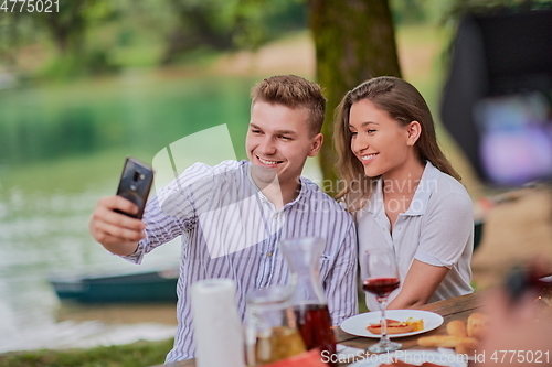 Image of couple taking selfie while having picnic french dinner party outdoor