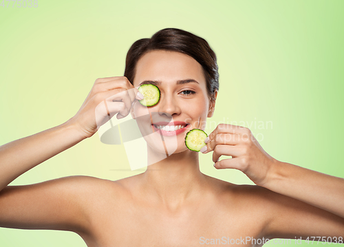 Image of beautiful woman making eye mask of cucumbers