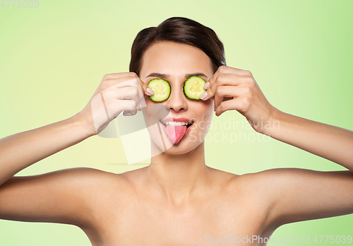 Image of beautiful woman making eye mask of cucumbers