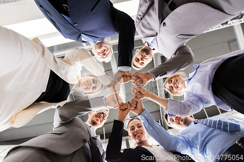 Image of happy business people making fist bump at office